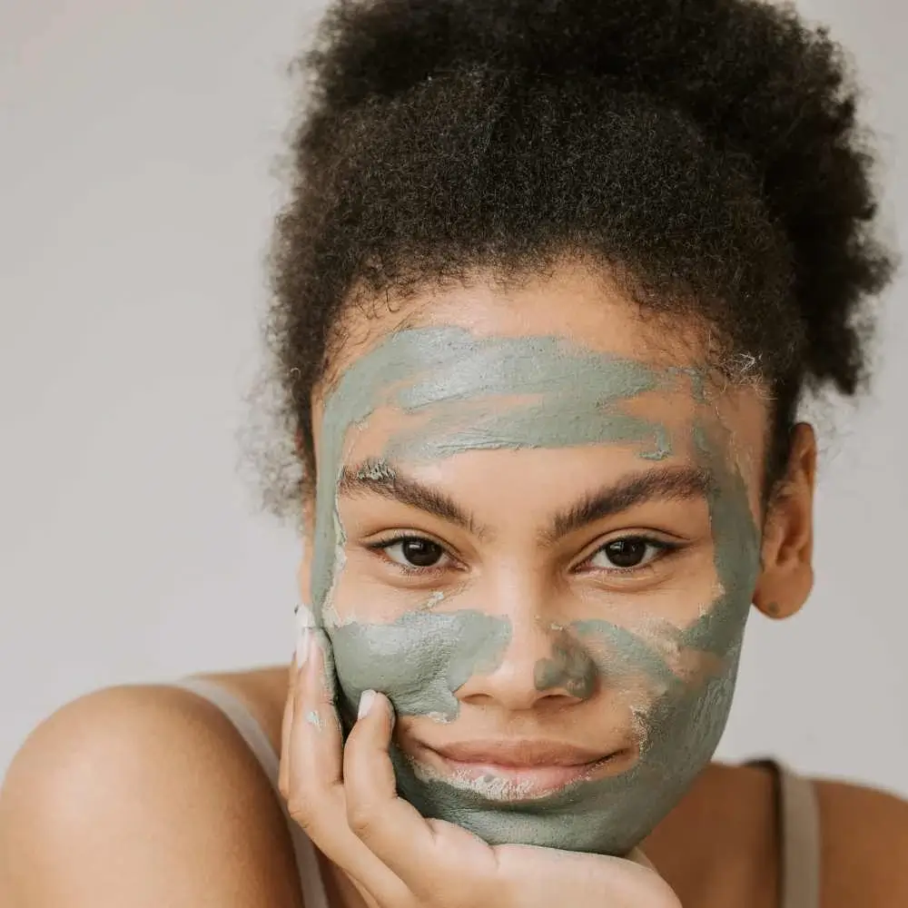 young woman with curly hair and clay face mask