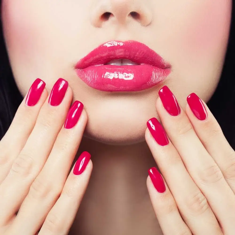 closeup shot of glossy bright pink lips and fuchsia nails