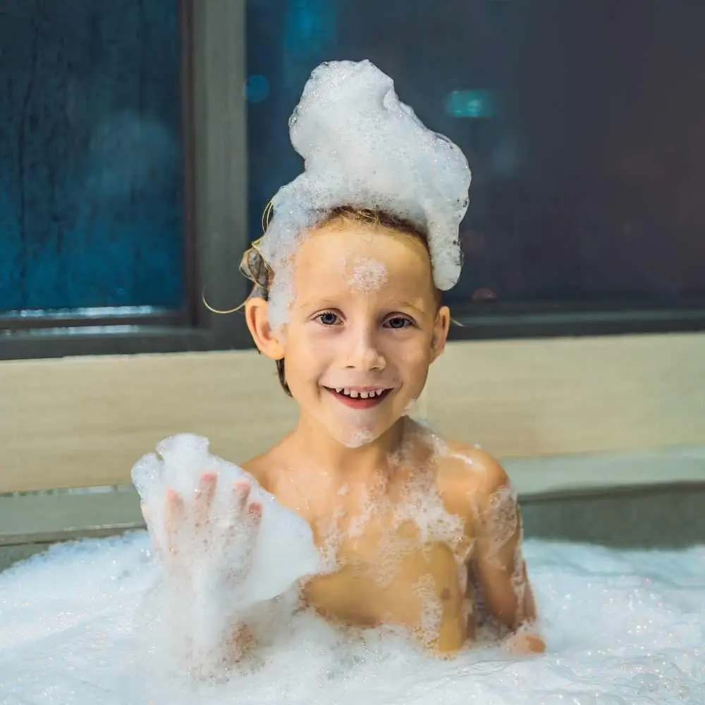 little boy sitting in a bath tub full of bubbles