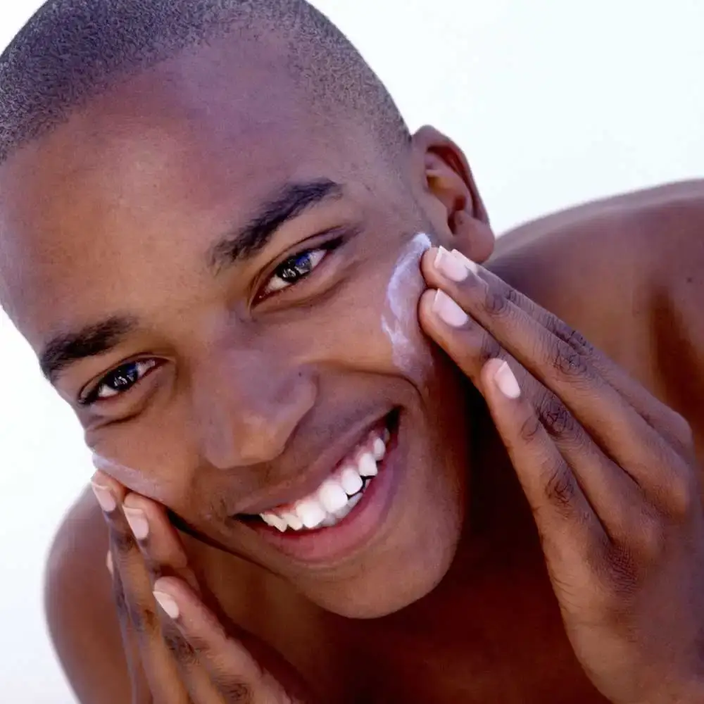 man smiling and applying vitamin c face wash