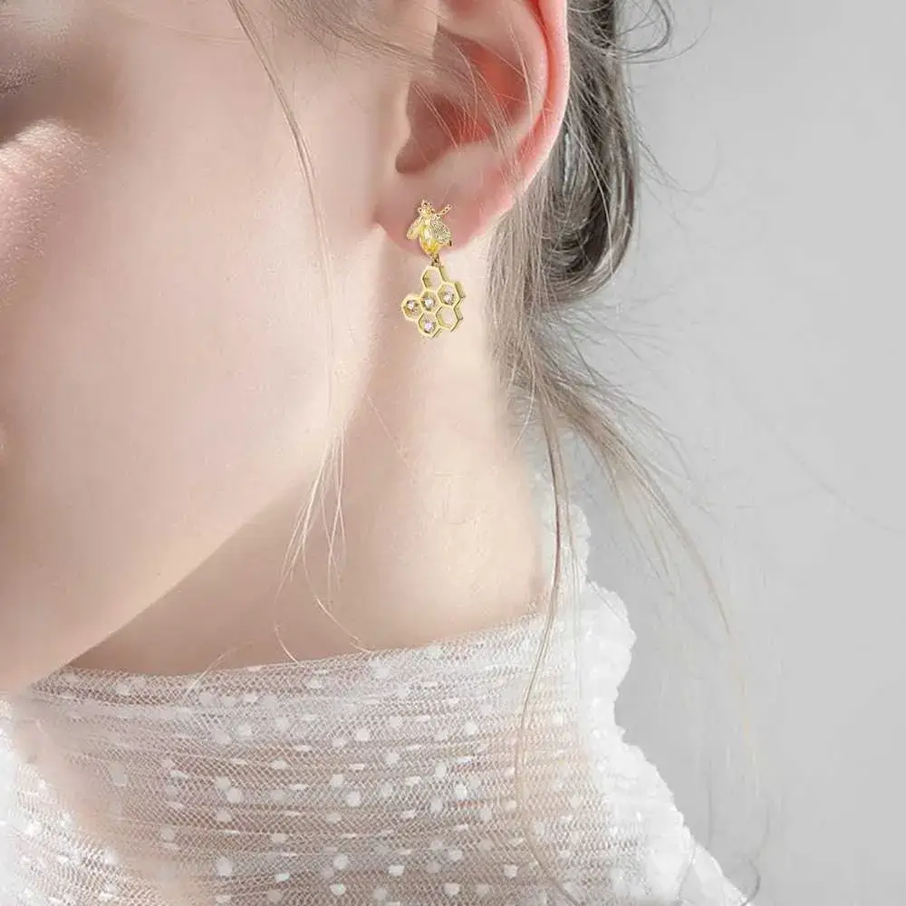 close-up view of a young woman's ear with gold honeycomb earrings