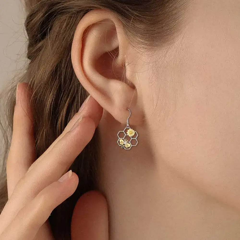 close-up view of a young woman's ear with silver honeycomb earrings with a flower and a bee