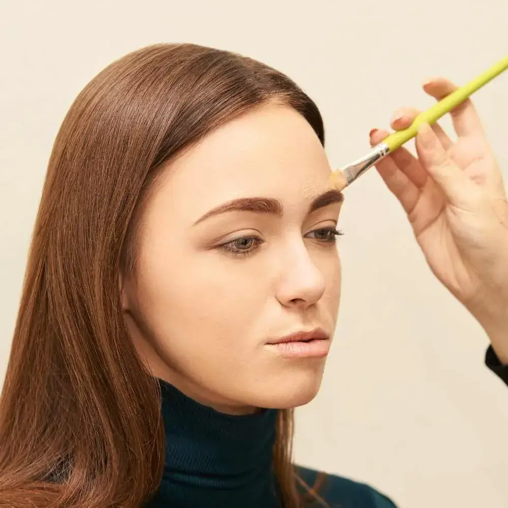 makeup artist applying concealer to a model