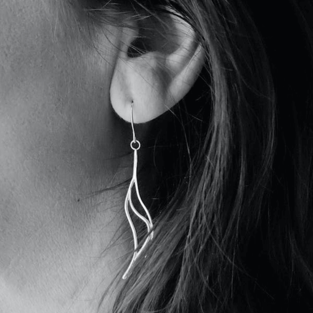 black and white image of woman's ear with twist earrings