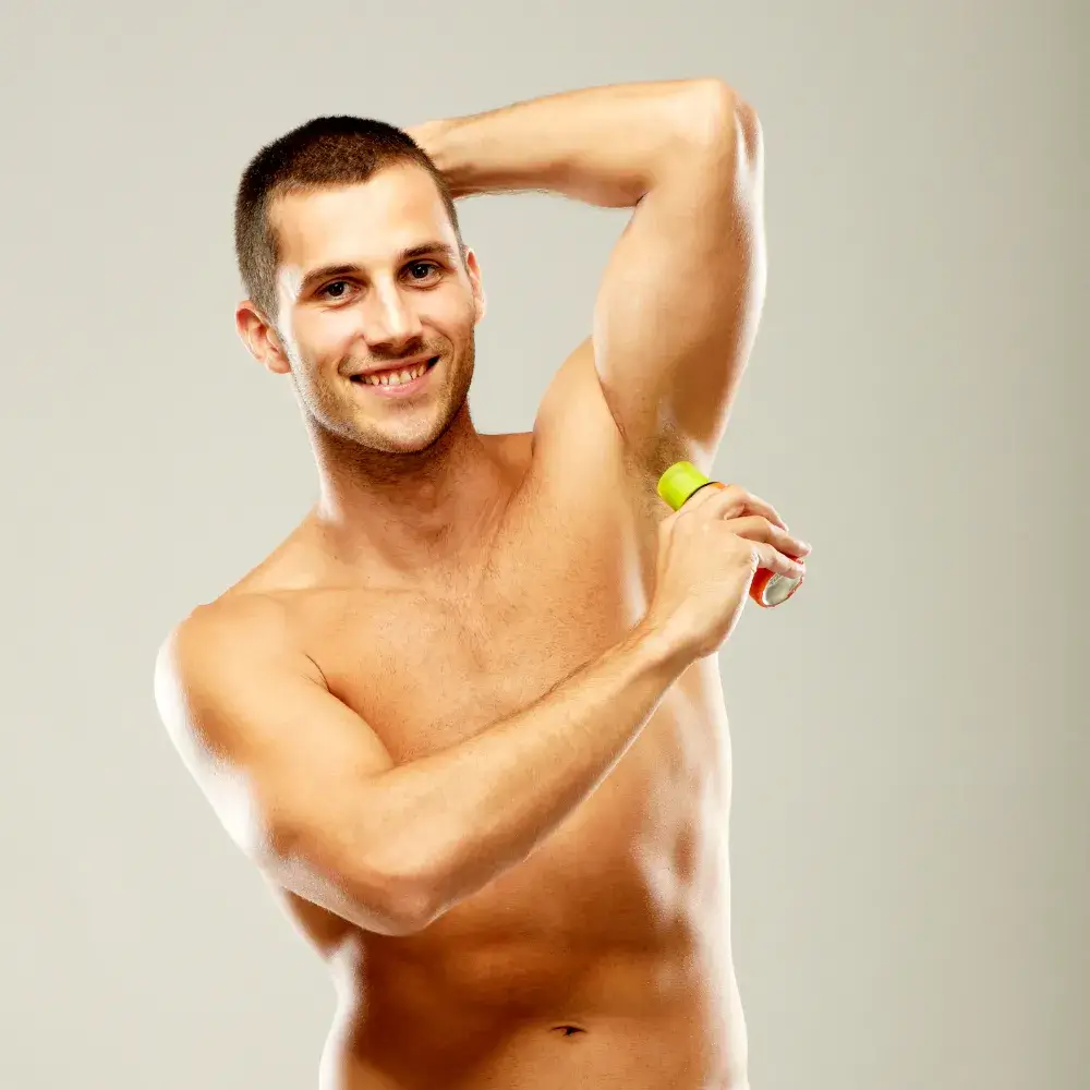 smiling man applying deodorant on his underarm